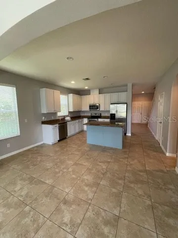 a large kitchen with stainless steel appliances granite countertop a stove a sink a refrigerator a microwave and cabinets