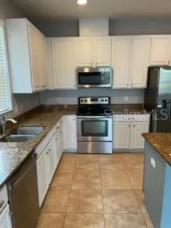 a kitchen with stainless steel appliances granite countertop a stove a sink and a microwave