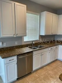 a kitchen with granite countertop white cabinets and sink