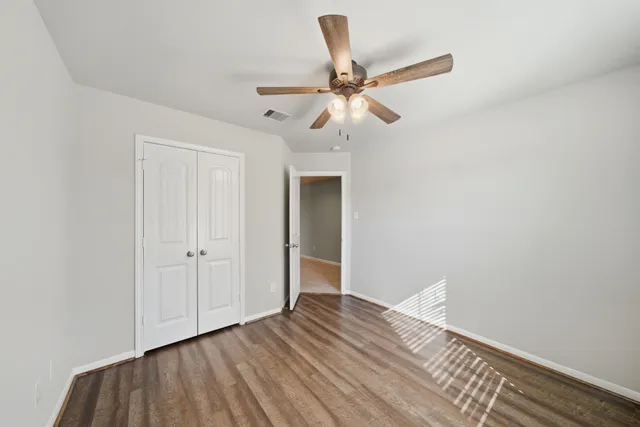 an empty room with a window and ceiling fan