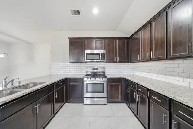 a kitchen with stainless steel appliances granite countertop a stove sink and cabinets