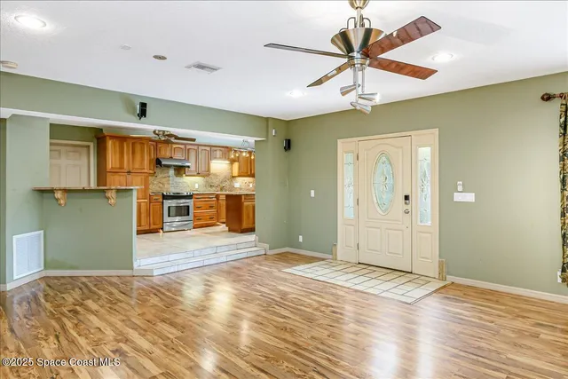 a view of empty room with wooden floor and fan