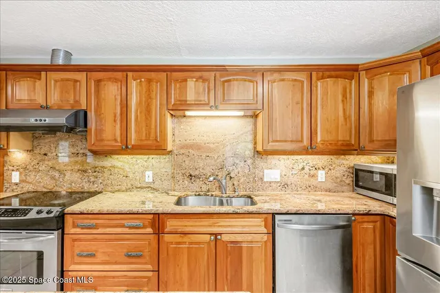 a kitchen with stainless steel appliances granite countertop a refrigerator and a sink
