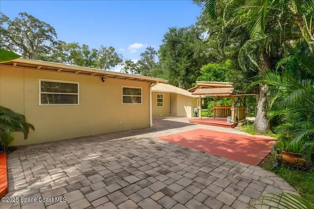 a view of a house with a yard and a large tree