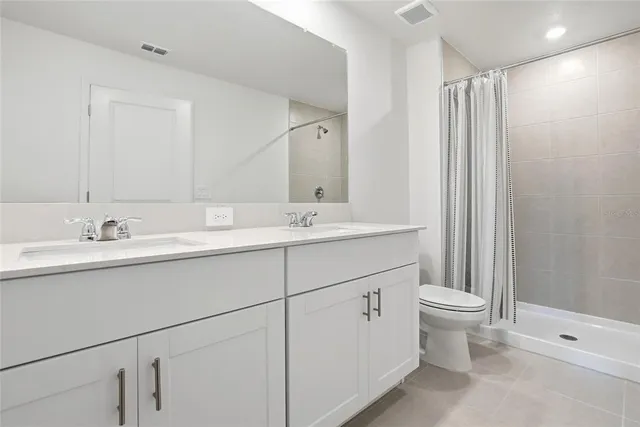 a bathroom with a double vanity sink a toilet and a mirror