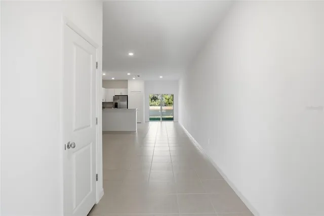 a view of a hallway with wooden floor windows and a kitchen