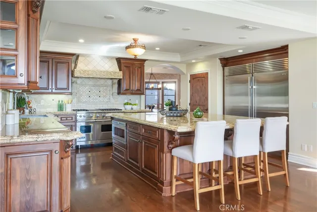 a kitchen with stainless steel appliances granite countertop a stove top oven a sink dishwasher a dining table and chairs with wooden floor