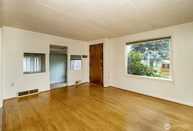 a view of empty room with wooden floor and fan