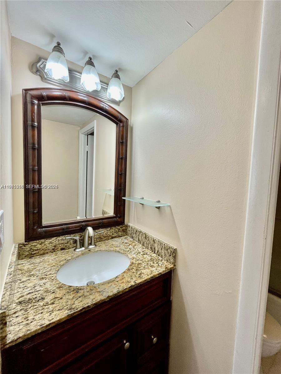 600 Three Islands Boulevard, Unit 1014 Hallandale Beach, FL 33009 - Photo 7 of 13 a bathroom with a granite countertop sink and a mirror