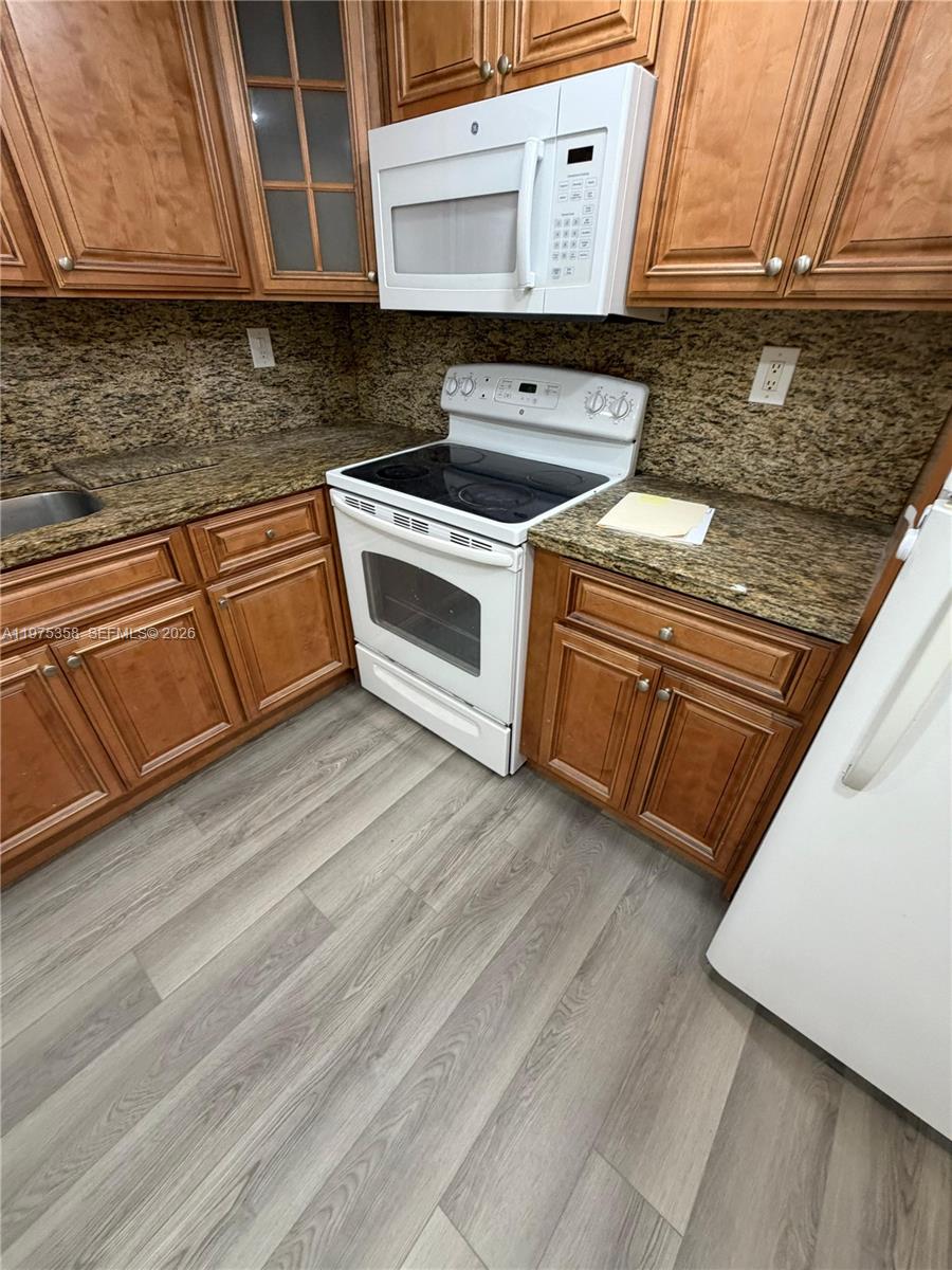 600 Three Islands Boulevard, Unit 1014 Hallandale Beach, FL 33009 - Photo 10 of 13 a kitchen with granite countertop a stove top oven and sink