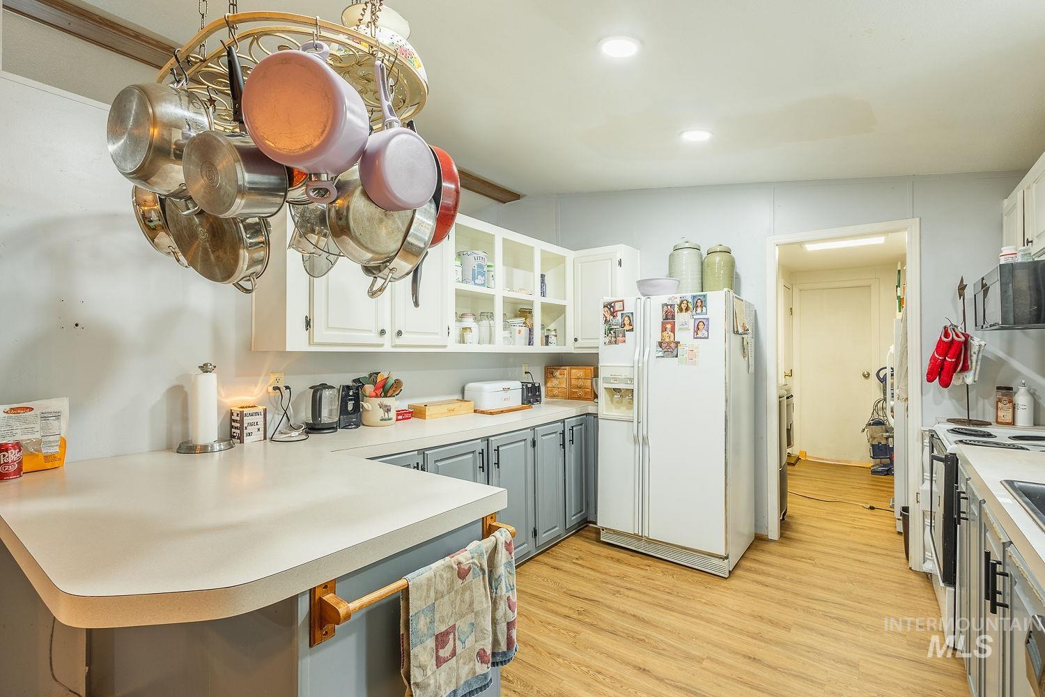 10 Reseda Ridge Circle Garden Valley, ID 83622 - Photo 14 of 28 Kitchen featuring white cabinets, a peninsula, white fridge with ice dispenser, light countertops, and electric stove