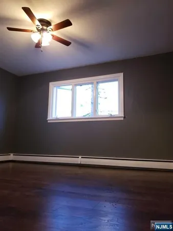 an empty room with wooden floor closet and windows