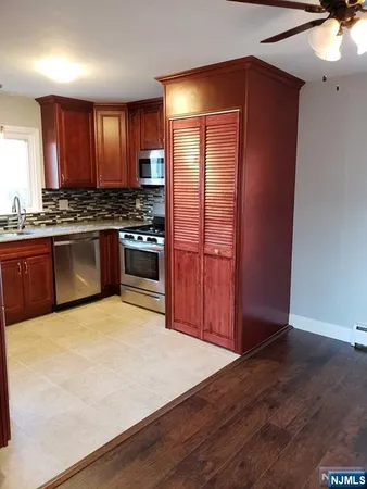 a large kitchen with granite countertop stainless steel appliances and wooden cabinets