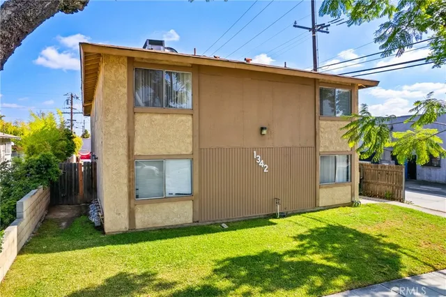 a backyard of a house with plants and large tree