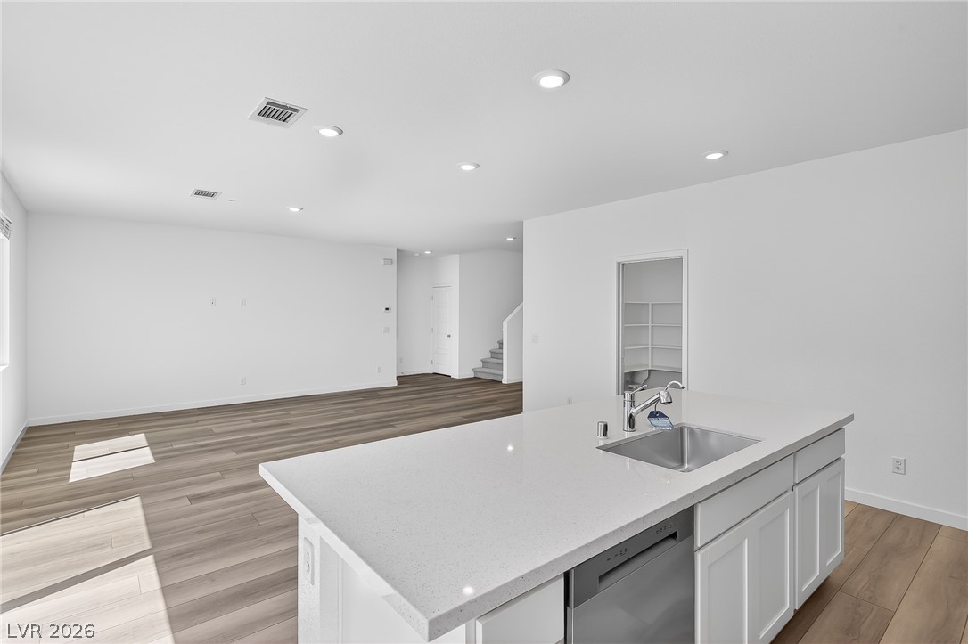 347 Sam Way Mesquite, NV 89027 - Photo 7 of 32 A pristine open-concept living space features light wood flooring and a kitchen island with integrated sink.