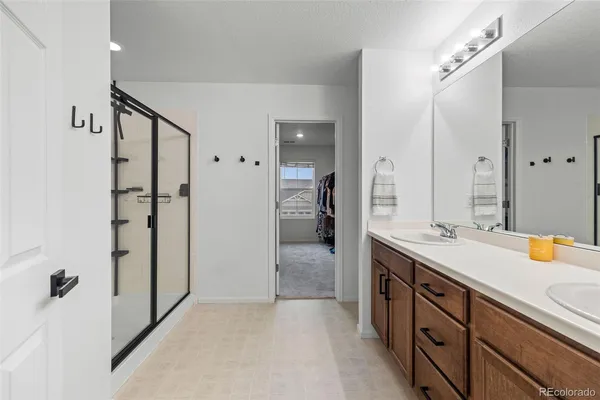 a spacious bathroom with a double vanity sink a large mirror and a shower