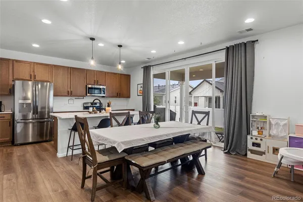 a kitchen with stainless steel appliances a dining table chairs stove refrigerator and wooden floor