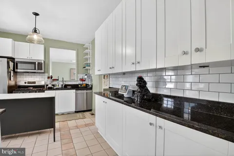 a kitchen with granite countertop a sink a stove and cabinets