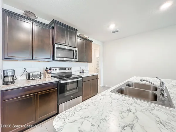 a kitchen with granite countertop a stove top oven a sink dishwasher a dining table and chairs