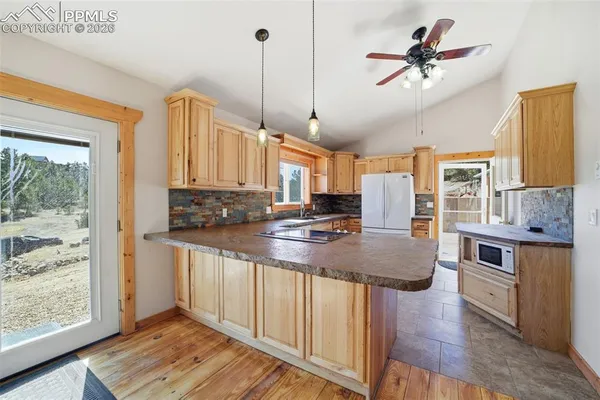 a kitchen with stainless steel appliances granite countertop a stove a sink dishwasher and a refrigerator with wooden floor