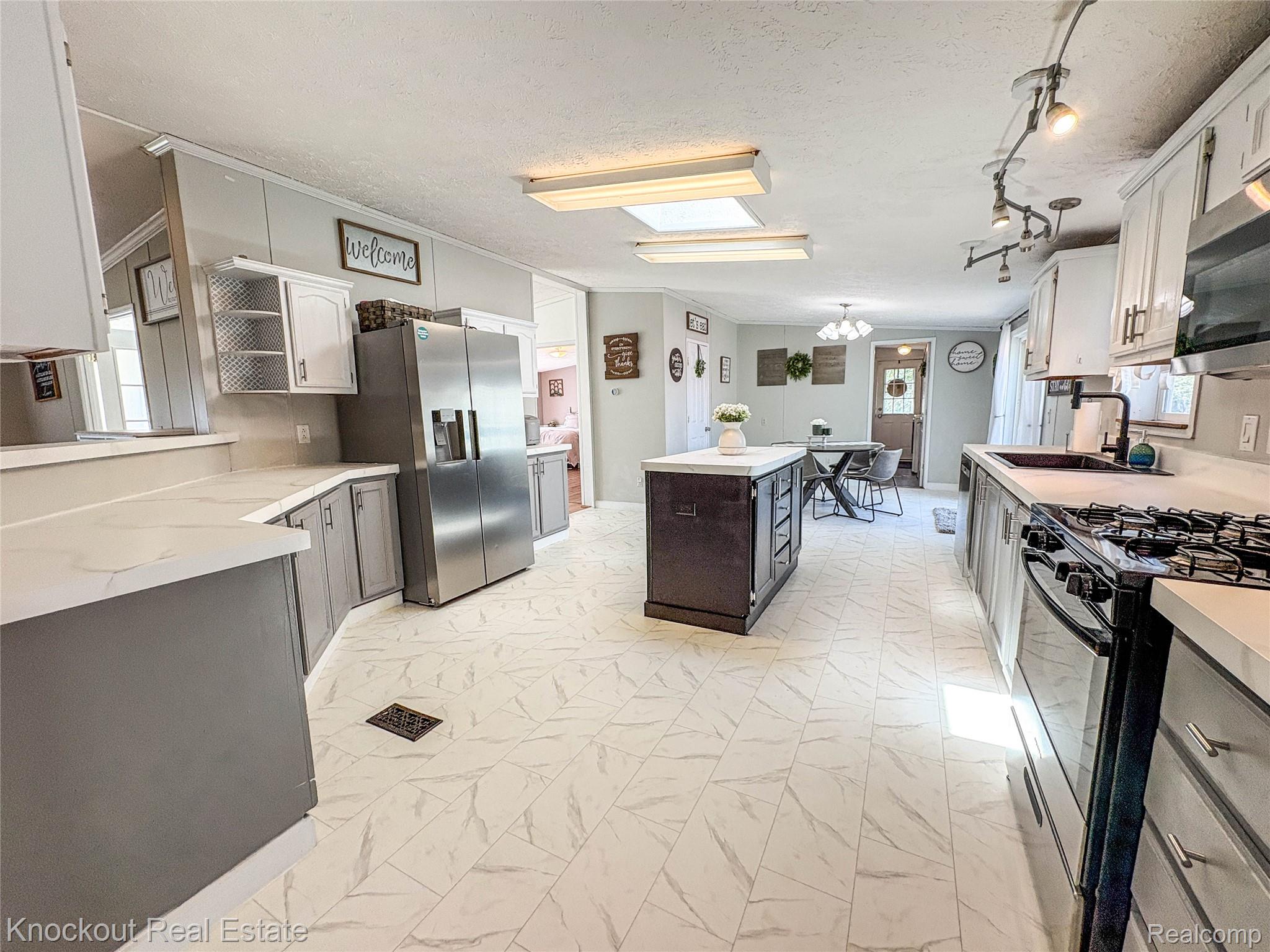7760 Bell Road Birch Run, MI 48415 - Photo 10 of 68 Spacious kitchen featuring an island, light-toned countertops, and two-tone cabinetry