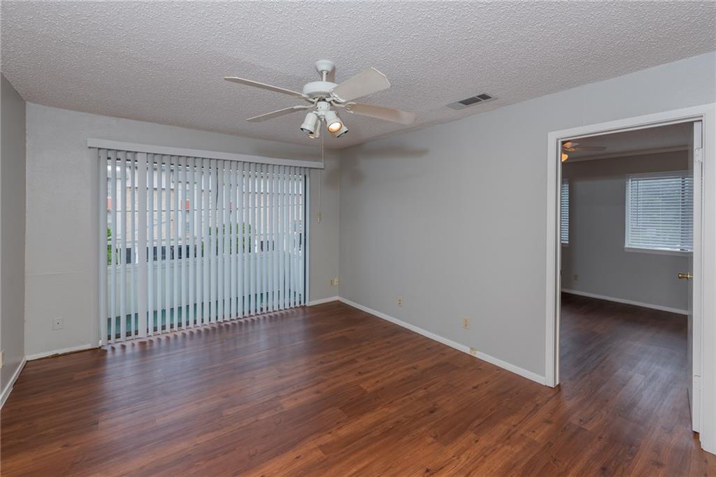 3115 Helms Street, Unit 116 Austin, TX 78705 - Photo 1 of 12 Empty room featuring a ceiling fan, a textured ceiling, and dark wood-style floors