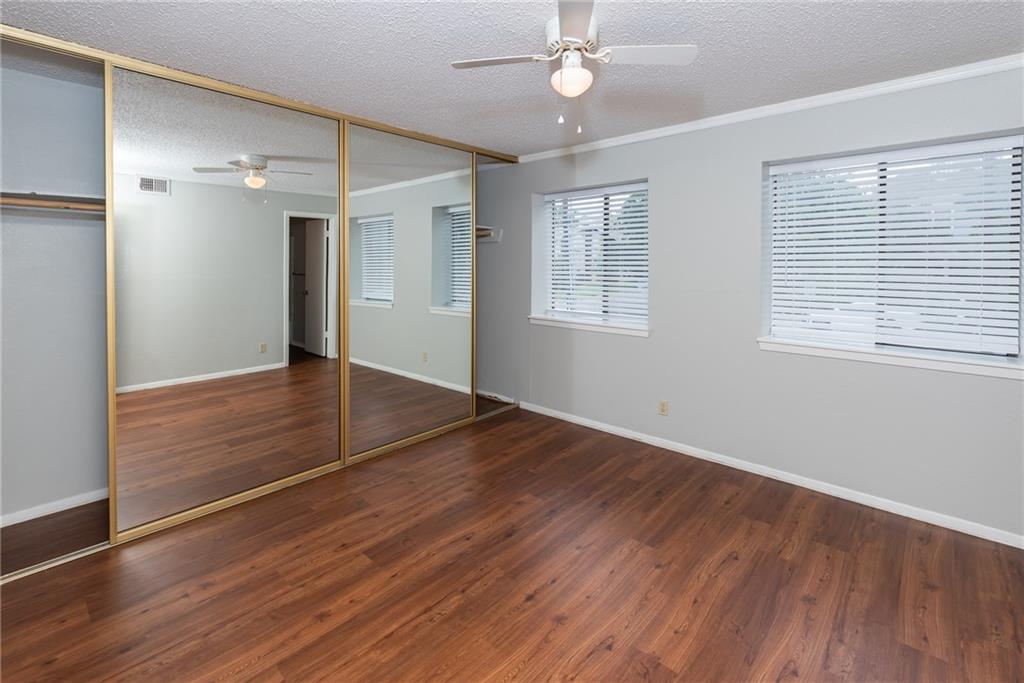 3115 Helms Street, Unit 116 Austin, TX 78705 - Photo 3 of 12 Unfurnished bedroom featuring dark wood-style floors, ceiling fan, a closet, a textured ceiling, and ornamental molding