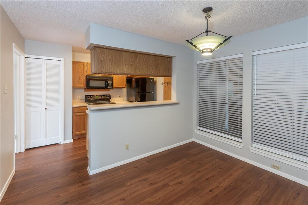 3115 Helms Street, Unit 116 Austin, TX 78705 - Photo 5 of 12 Kitchen with light countertops, black appliances, dark wood-style floors, a textured ceiling, and decorative light fixtures