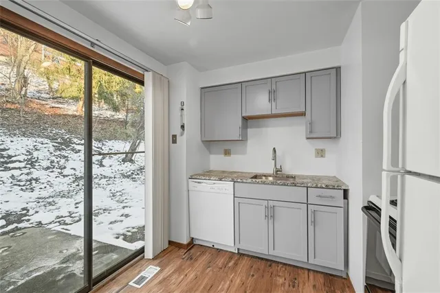 a kitchen with stainless steel appliances granite countertop a refrigerator a sink a stove and white cabinets with wooden floor