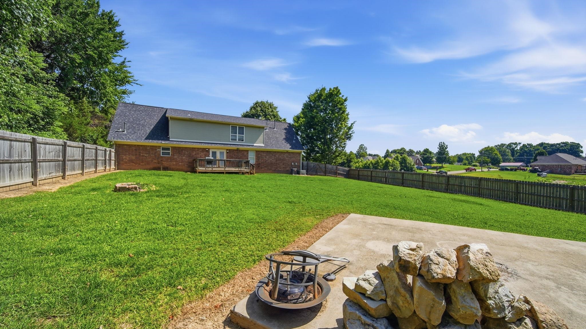 217 Rae Drive Munford, TN 38058 - Photo 37 of 40 Expansive backyard featuring a lush lawn, privacy fencing, and a concrete pad.