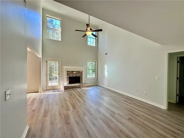 an empty room with wooden floor fireplace and windows