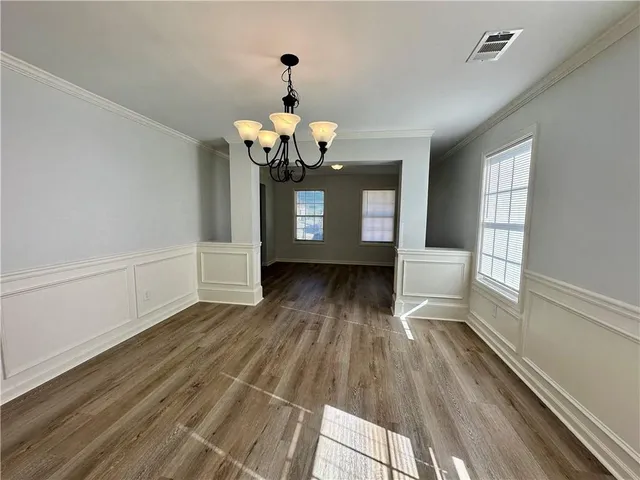 a view of a room with wooden floor table and chairs