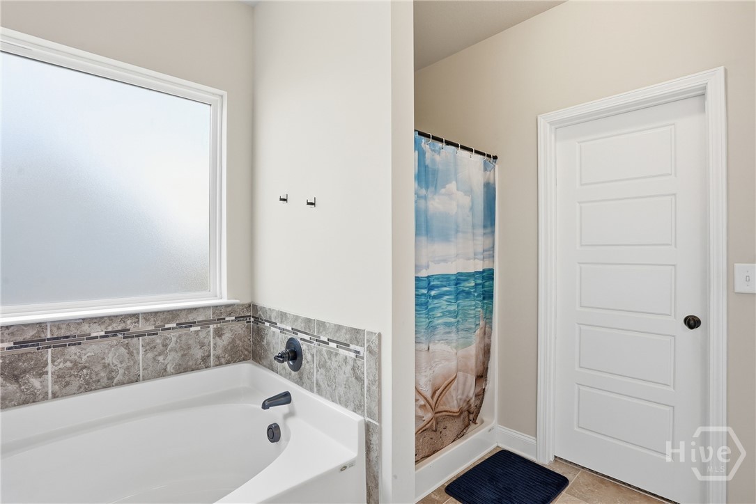 313 Crosswinds Drive Rincon, GA 31326 - Photo 19 of 34 Bathroom with tiled bathtub, frosted privacy window, neutral wall color, light-colored flooring, and white panel door.