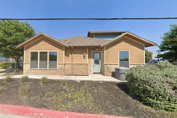 a front view of a house with a yard and potted plants