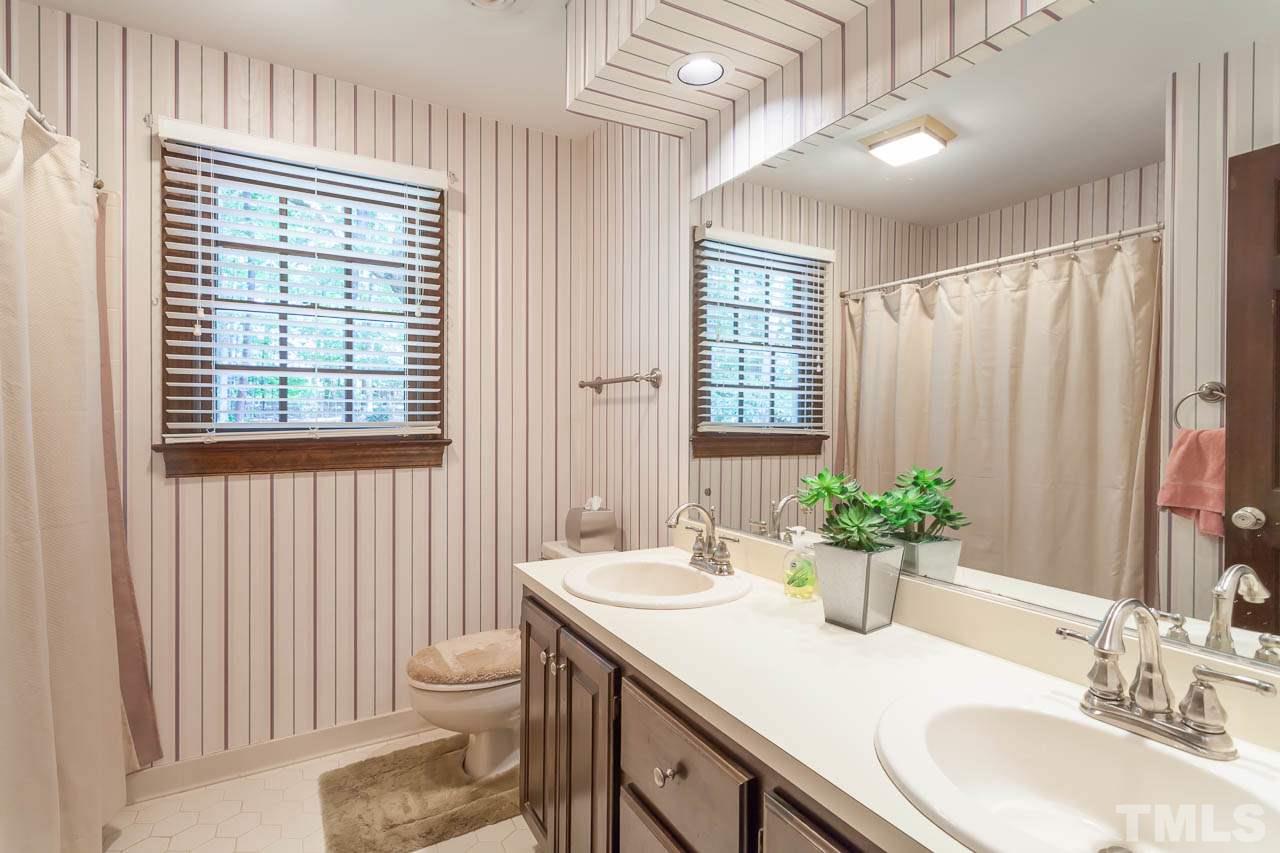 2901 Patrie Place Raleigh, NC 27613 - Photo 20 of 25 a bathroom with a granite countertop sink a toilet and a large mirror
