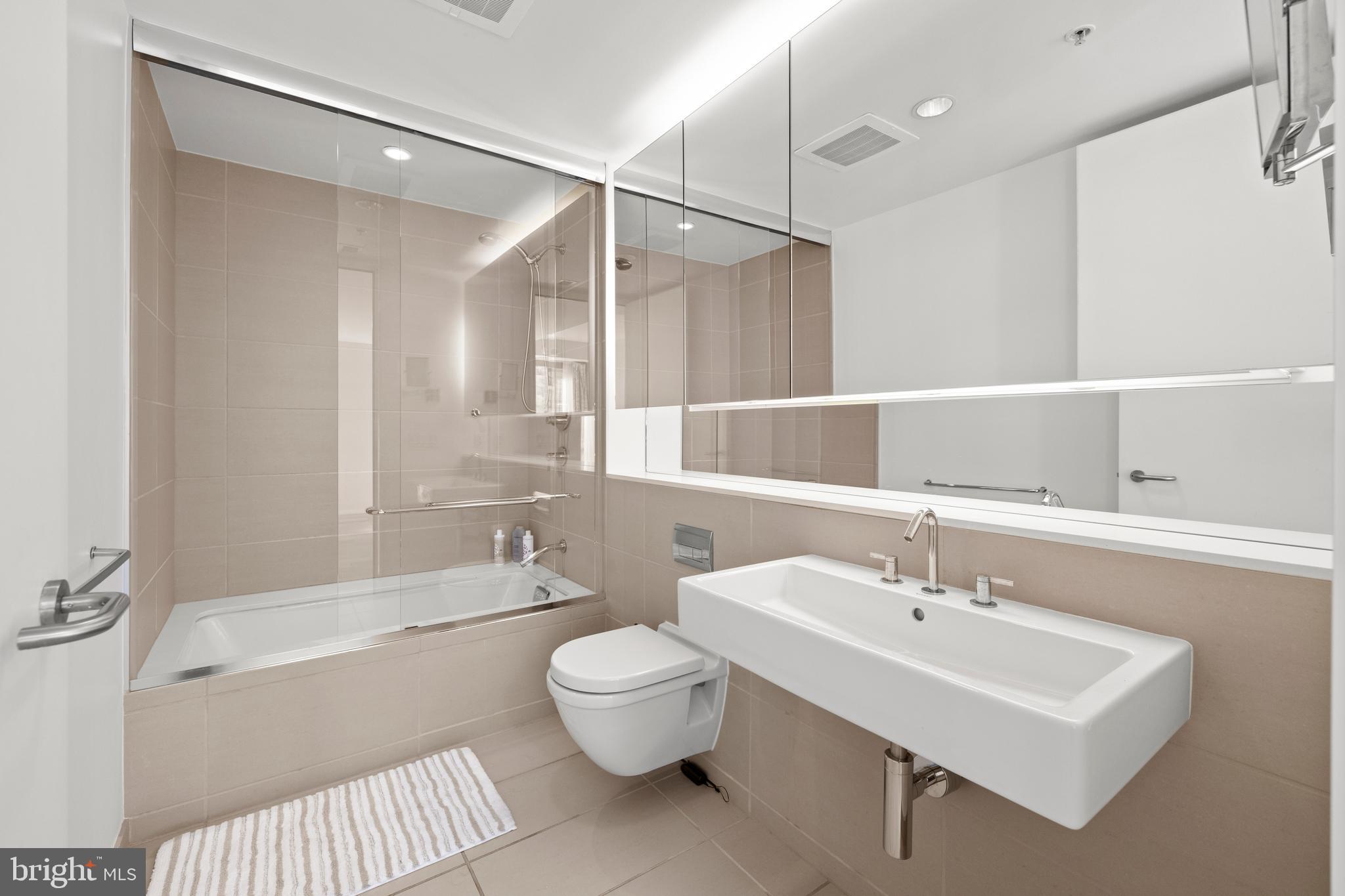 920 I Street Northwest, Unit 504505 Washington, DC 20001 - Photo 45 of 68 a bathroom with a sink toilet a mirror and shower