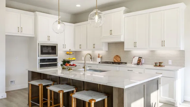 a kitchen with stainless steel appliances a sink a stove a refrigerator and white cabinets with wooden floor