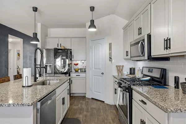 a kitchen with stainless steel appliances a kitchen island a stove a table and chairs in it