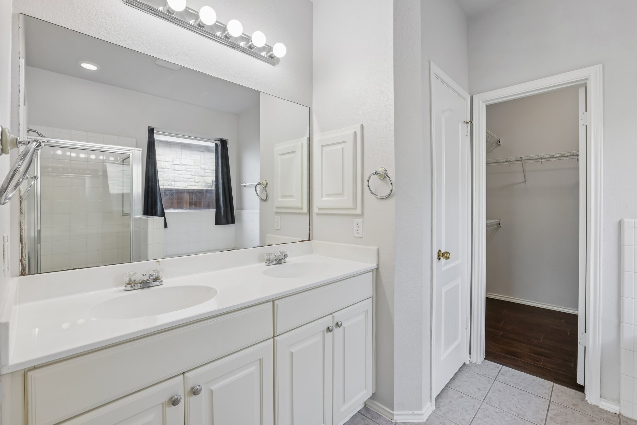 1721 Long Rifle Drive Austin, TX 78754 - Photo 14 of 38 A well-lit bathroom with a double vanity and a glass-enclosed shower.