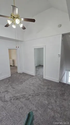 a view of an empty room with a chandelier fan