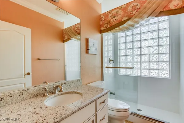 a bathroom with a granite countertop sink toilet and shower