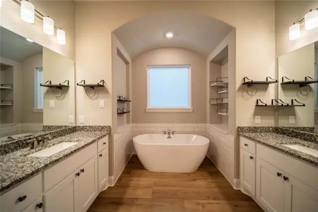 a bathroom with a granite countertop sink a mirror and a bathtub