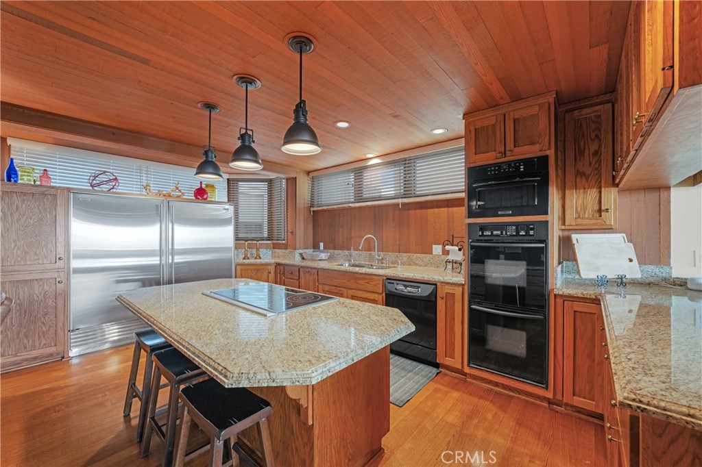 72-B Surfside Avenue Surfside, CA 90743 - Photo 27 of 56 a kitchen with stainless steel appliances granite countertop a sink a microwave and wooden cabinets
