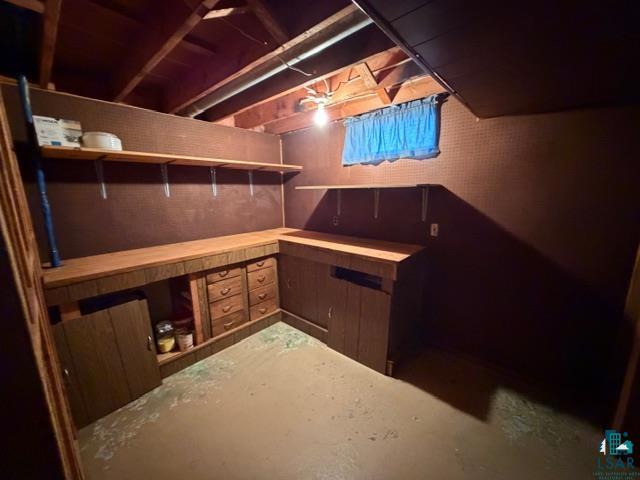 50 Beech Circle Babbitt, MN 55706 - Photo 16 of 24 Utility space featuring a wood-finish workbench with integrated drawers, open shelving, and exposed ceiling joists
