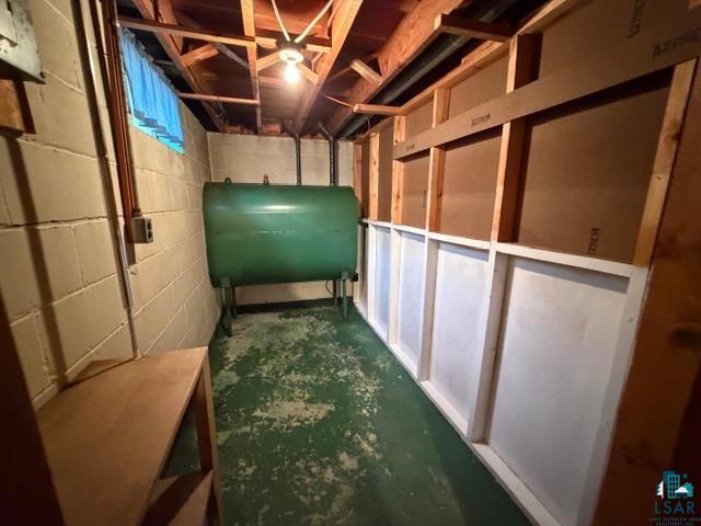 50 Beech Circle Babbitt, MN 55706 - Photo 17 of 24 Basement space featuring exposed ceiling joists, concrete block walls, and a visible utility tank