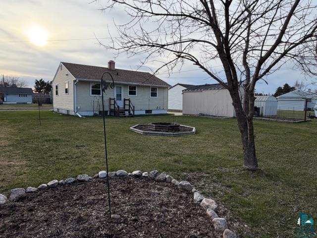 50 Beech Circle Babbitt, MN 55706 - Photo 21 of 24 Expansive backyard featuring a central fire pit area, a rock-bordered garden bed, and a large storage shed