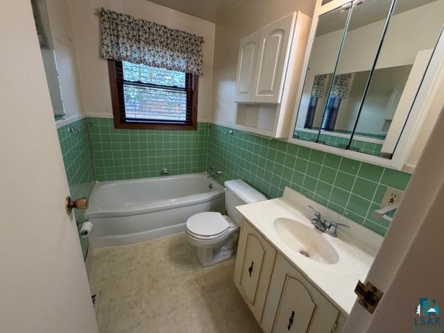 50 Beech Circle Babbitt, MN 55706 - Photo 9 of 24 Bathroom featuring a built-in bathtub, green tiled walls, a vanity with an integrated sink, and a mirrored medicine cabinet