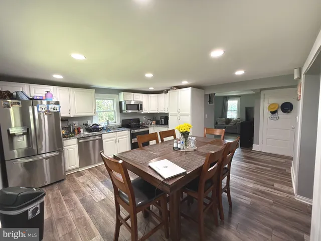 a kitchen with a dining table chairs and refrigerator