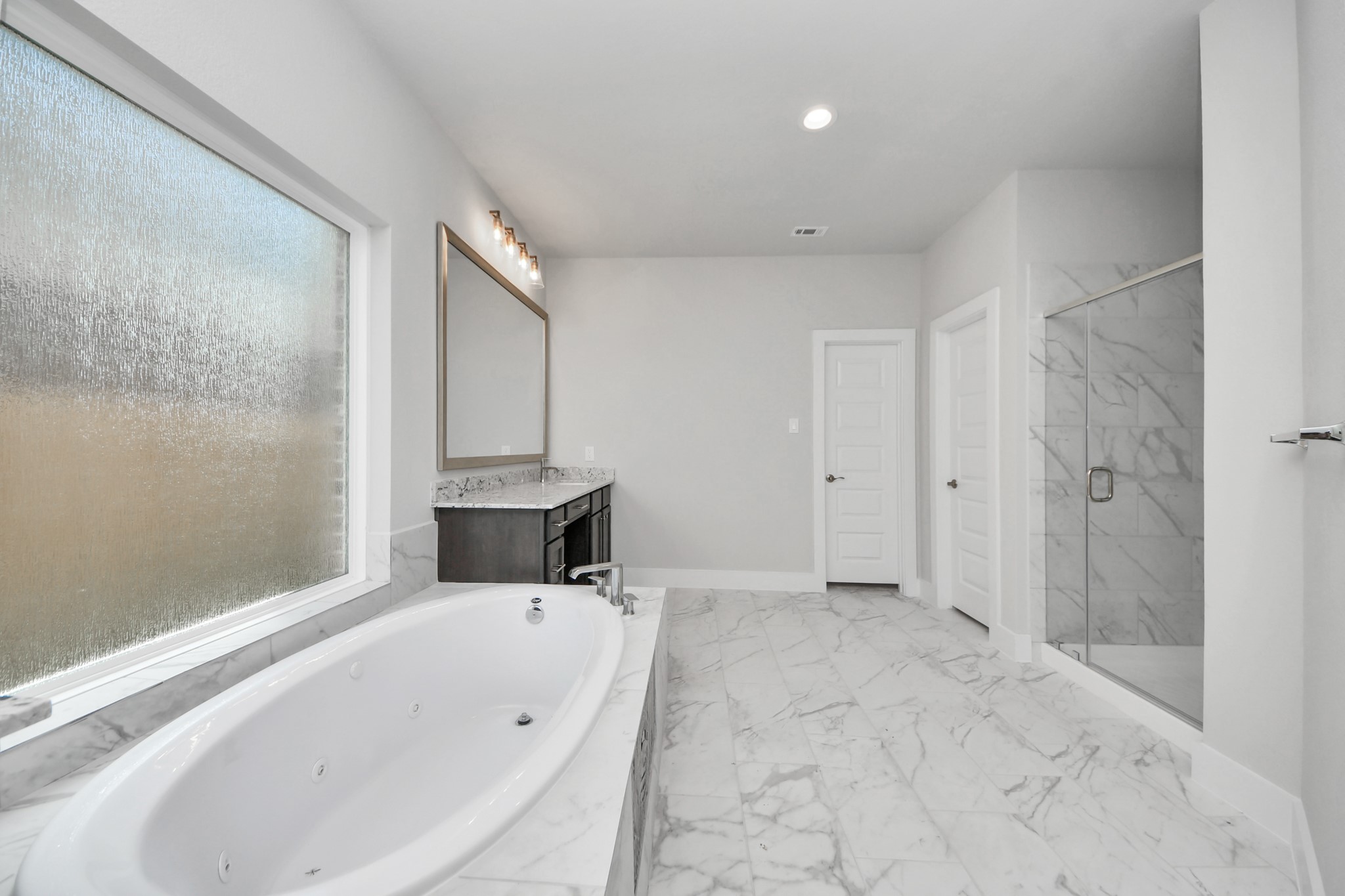 3023 Native Spg Drive Spring, TX 77373 - Photo 25 of 50 Indulge in a spa-like retreat within the confines of this primary bathroom. Delight in a spacious walk-in shower enveloped in stylish tile surround, unwind in a separate garden tub adorned with custom detailing.