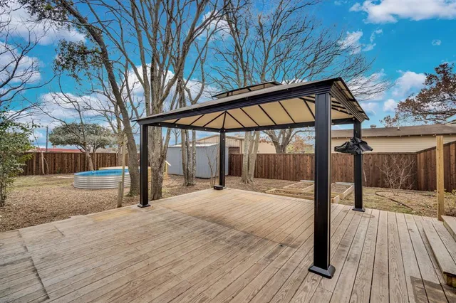 a backyard of a house with wooden floor and fence next to a yard